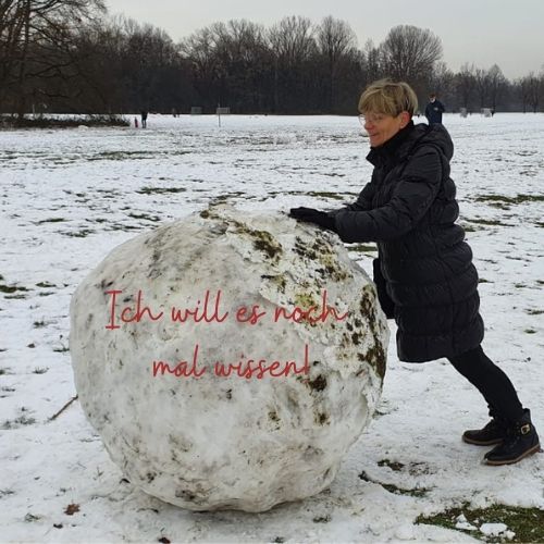 Auf dem Bild sieht man eine Frau, die versucht, eine riesige Schneekugel zu bewegen.