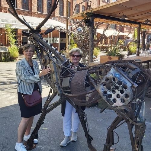 Zwei Frauen stehen neben einer Metallskulptur