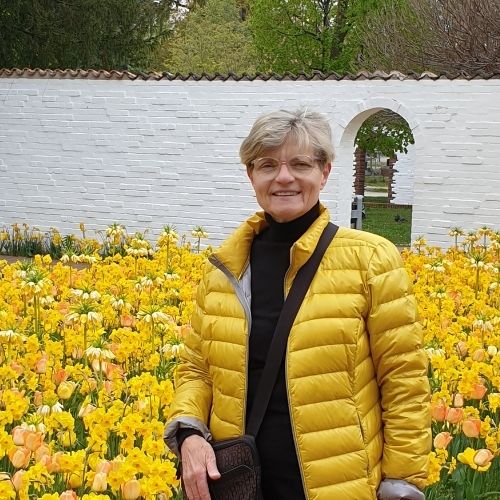 Eine Frau in gelber Jacke im gelben Tulpenfeld