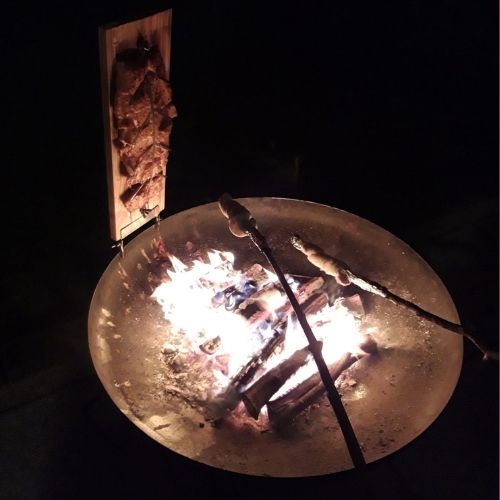 Eine Feuerschale im Dunkeln mit Stockbrot und loderndem Feuer